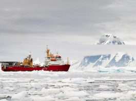 The red-hulled Royal Navy ice patrol ship HMS Protector among sea ice off Galindez Island, Antarctica, with snow-covered mountains behind, file photograph