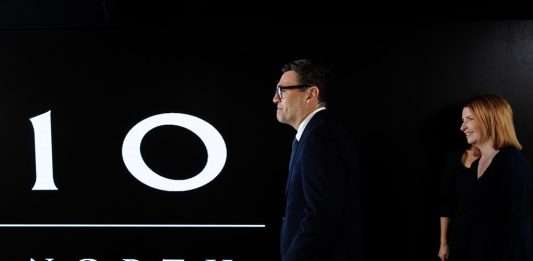 Prime Minister Andy Burnham walks past a large illuminated 10 North sign at the No 10 North office in Manchester