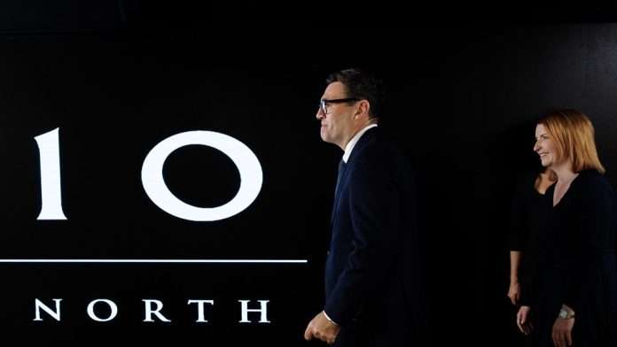 Prime Minister Andy Burnham walks past a large illuminated 10 North sign at the No 10 North office in Manchester