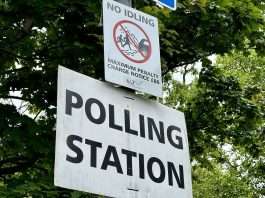 A white Polling Station sign on a lamp post among trees at Shepherd's Bush Green, London, file photograph